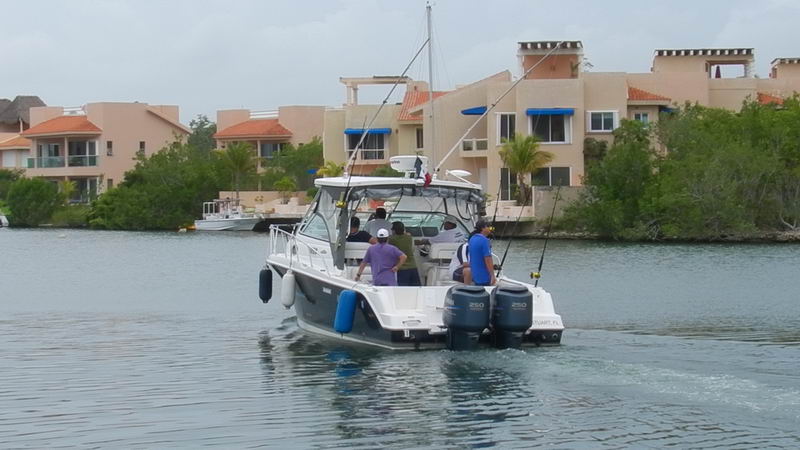 Vista de popa de la Wellcraft 30 pies con doble motor 250hp y pasajeros saliendo de marina Puerto Aventuras pesca Riviera Maya