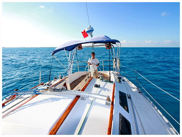 Captain at helm of 42 ft Jeanneau sailboat cruising open Caribbean Sea on luxury sailing charter from Cancun